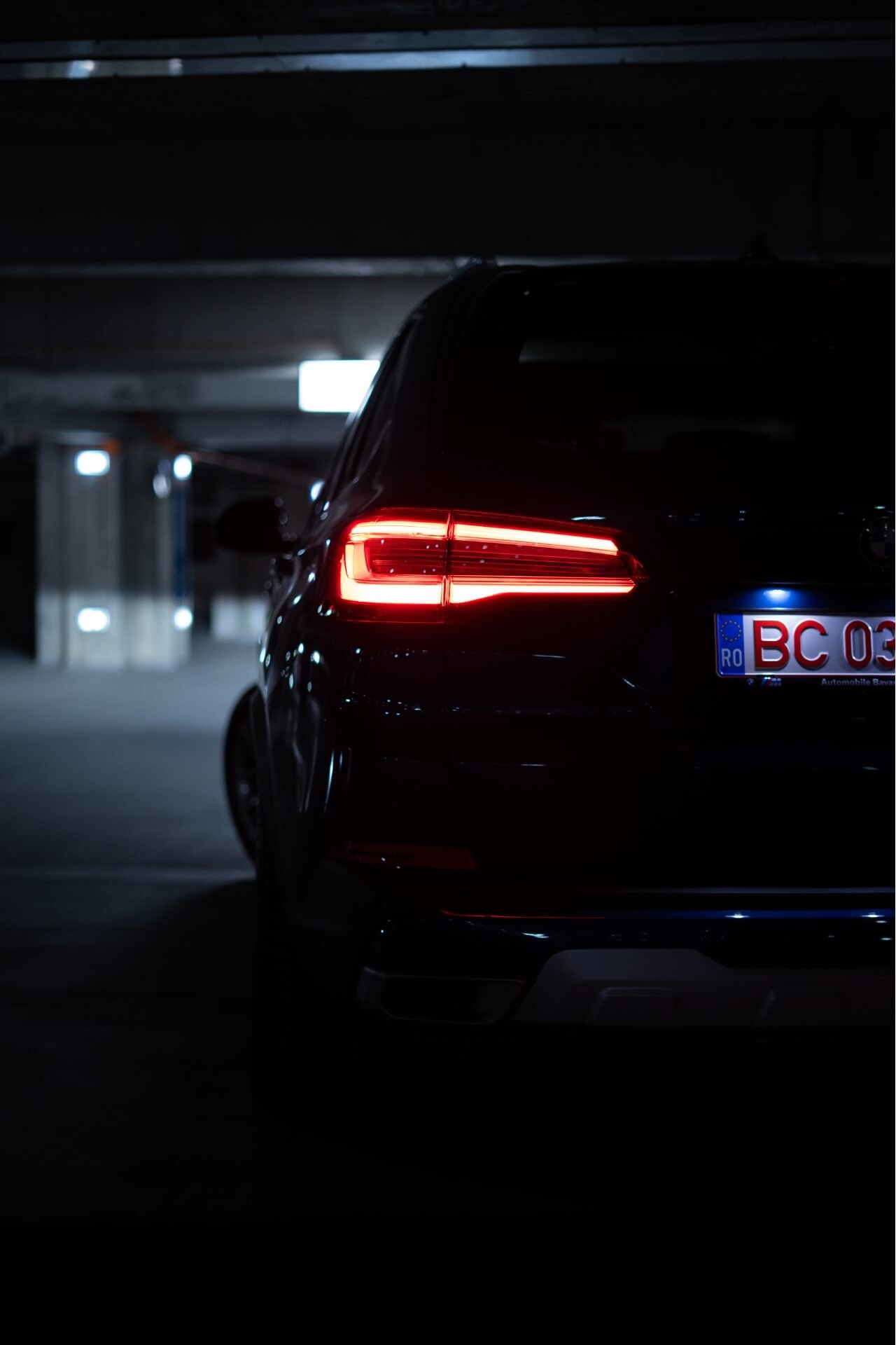 Back of a BMW X5 in a dark background parking lot