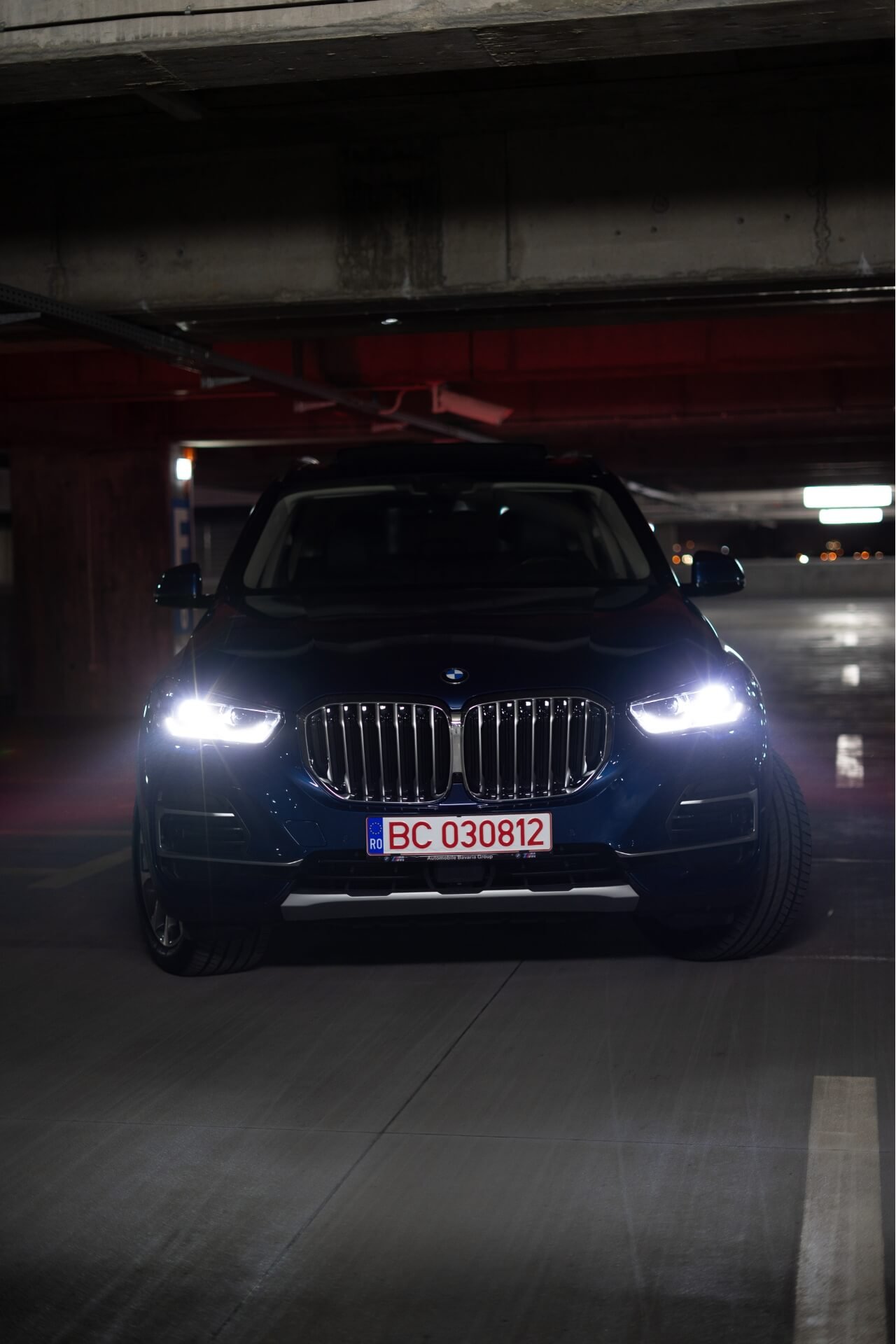 Front part of a dark blue BMW X5 in a parking lot
