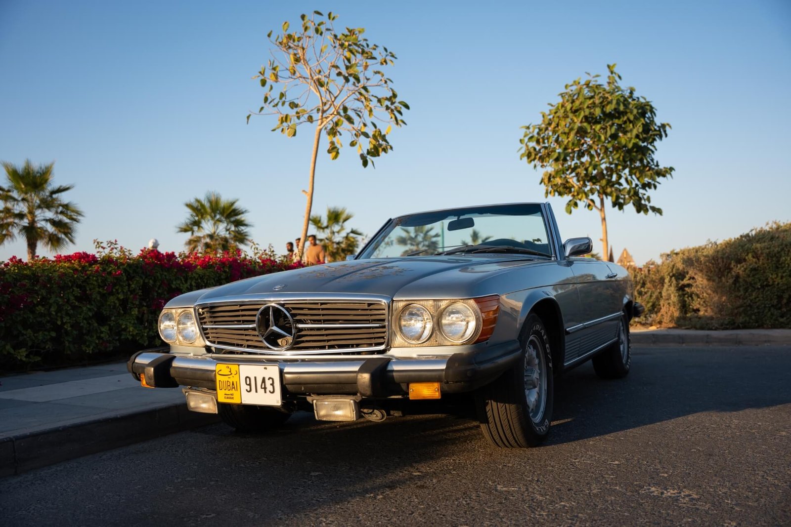 An old Mercedes Benz cabrio parked next to Kite Beach with nice scenery in the back during sunset