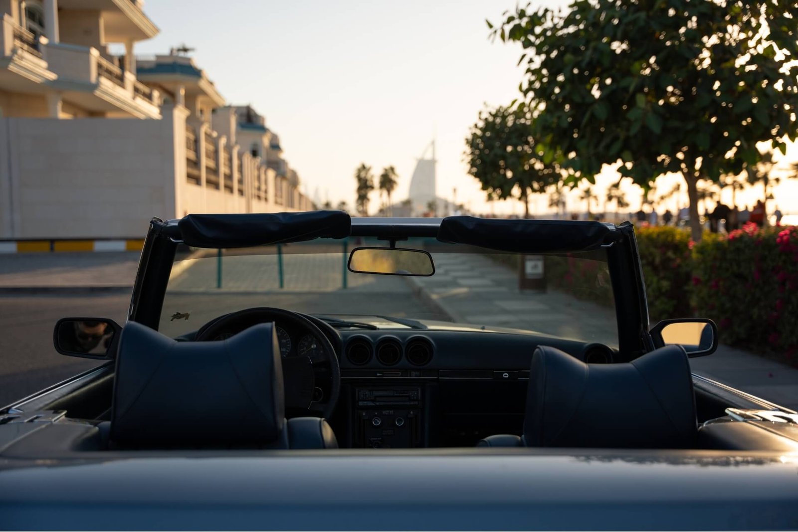 The interior of an old Mercedes Benz cabrio with Burj Al Arab seen far away in the background