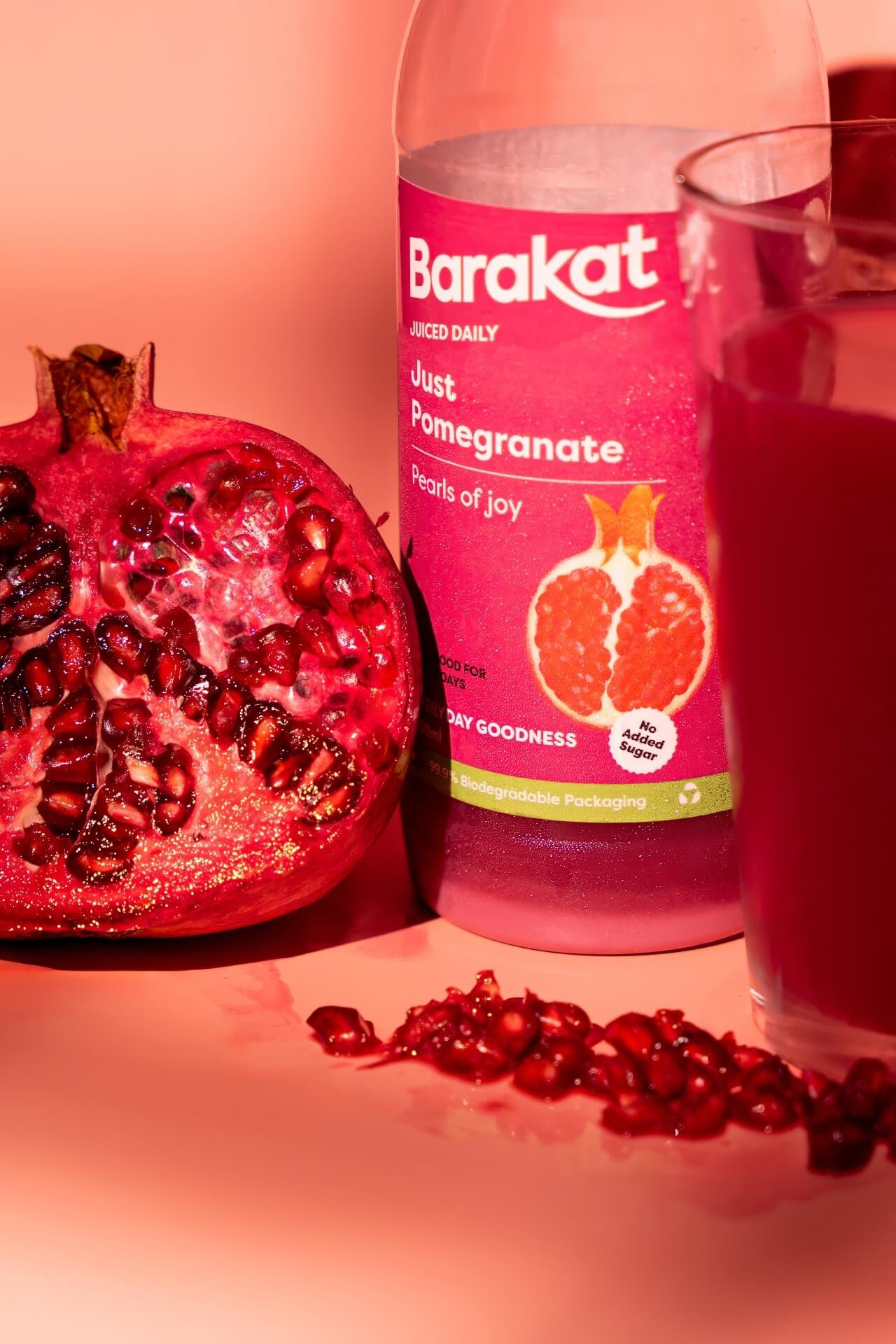 Barakat Pomegranate bottle and pomegranate pieces laying down