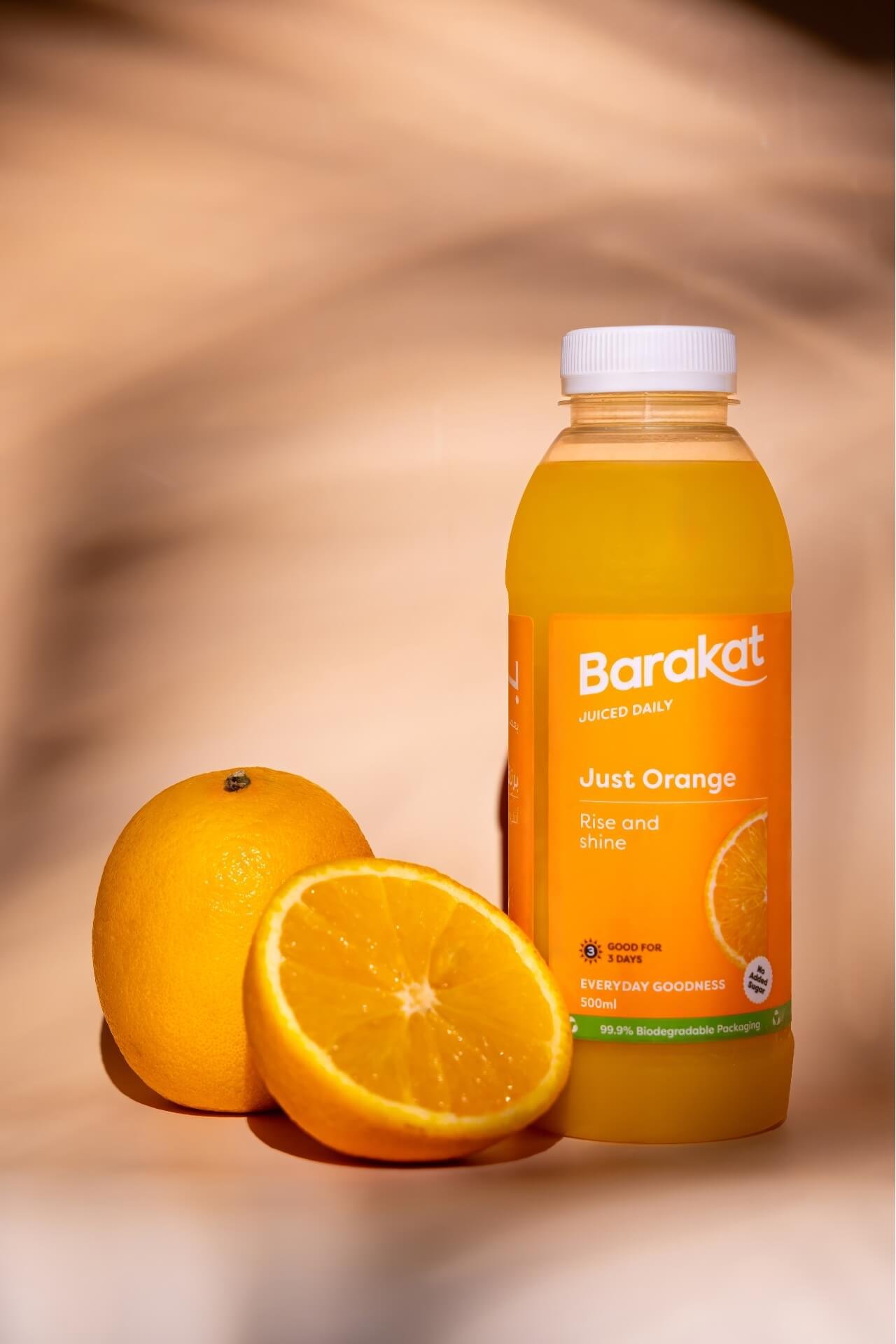 Orange sliced in half next to a Barakat orange juice bottle