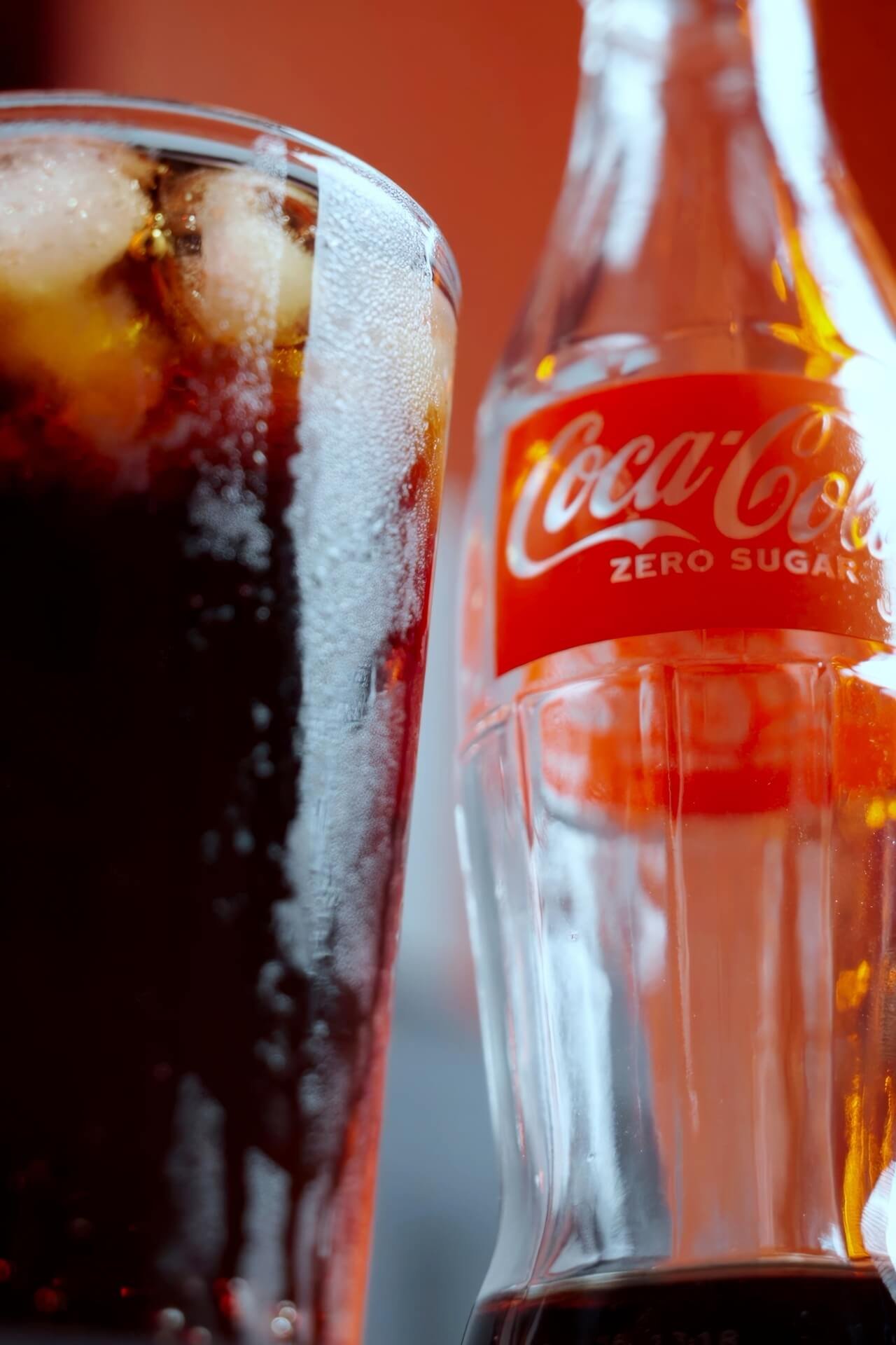 Coca-Cola Zero Sugar bottle with a glass full of Coke next to it with water drops on the glass