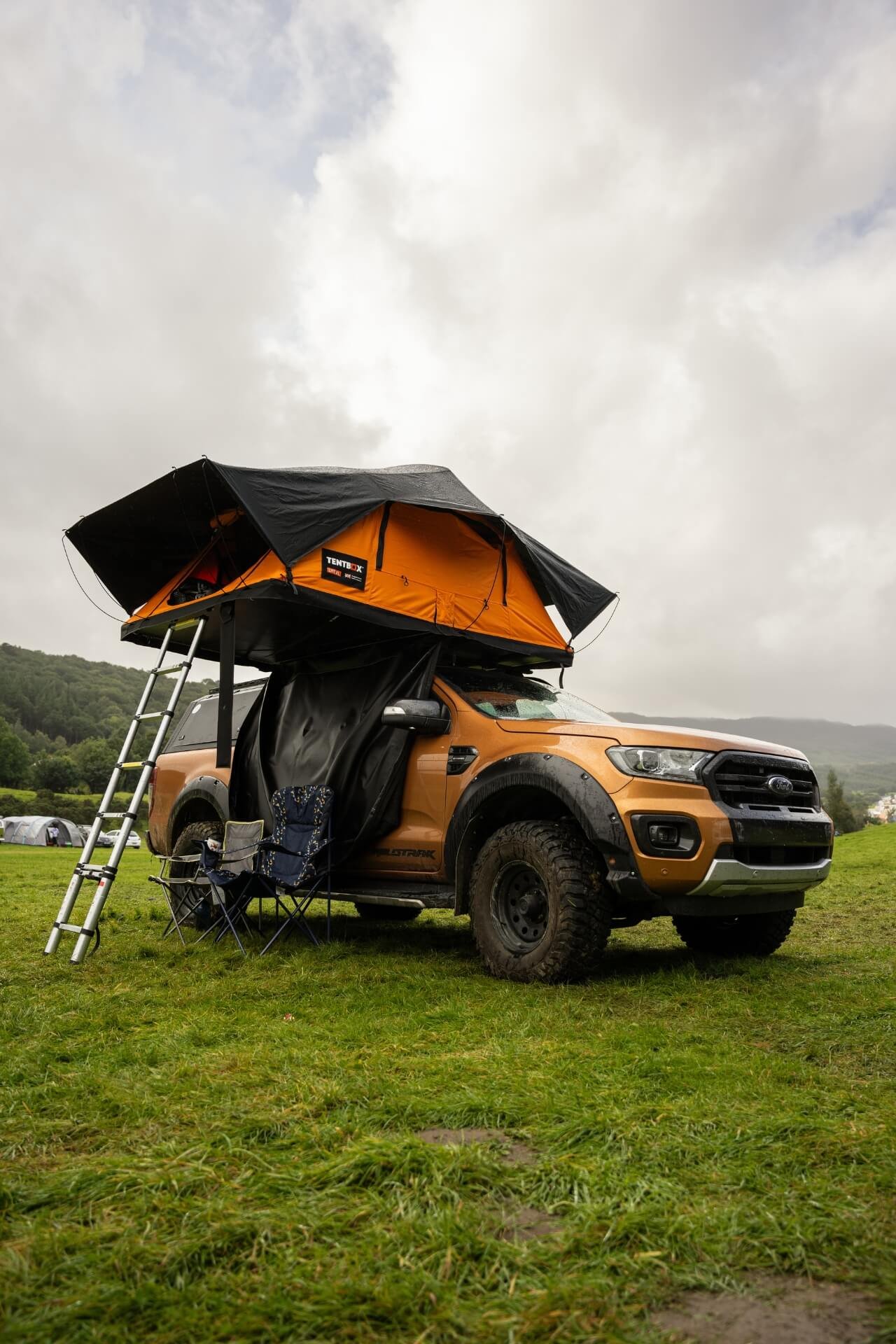 Tentbox tent open with ladder on top of a Ford Ranger in a camping area in Wales