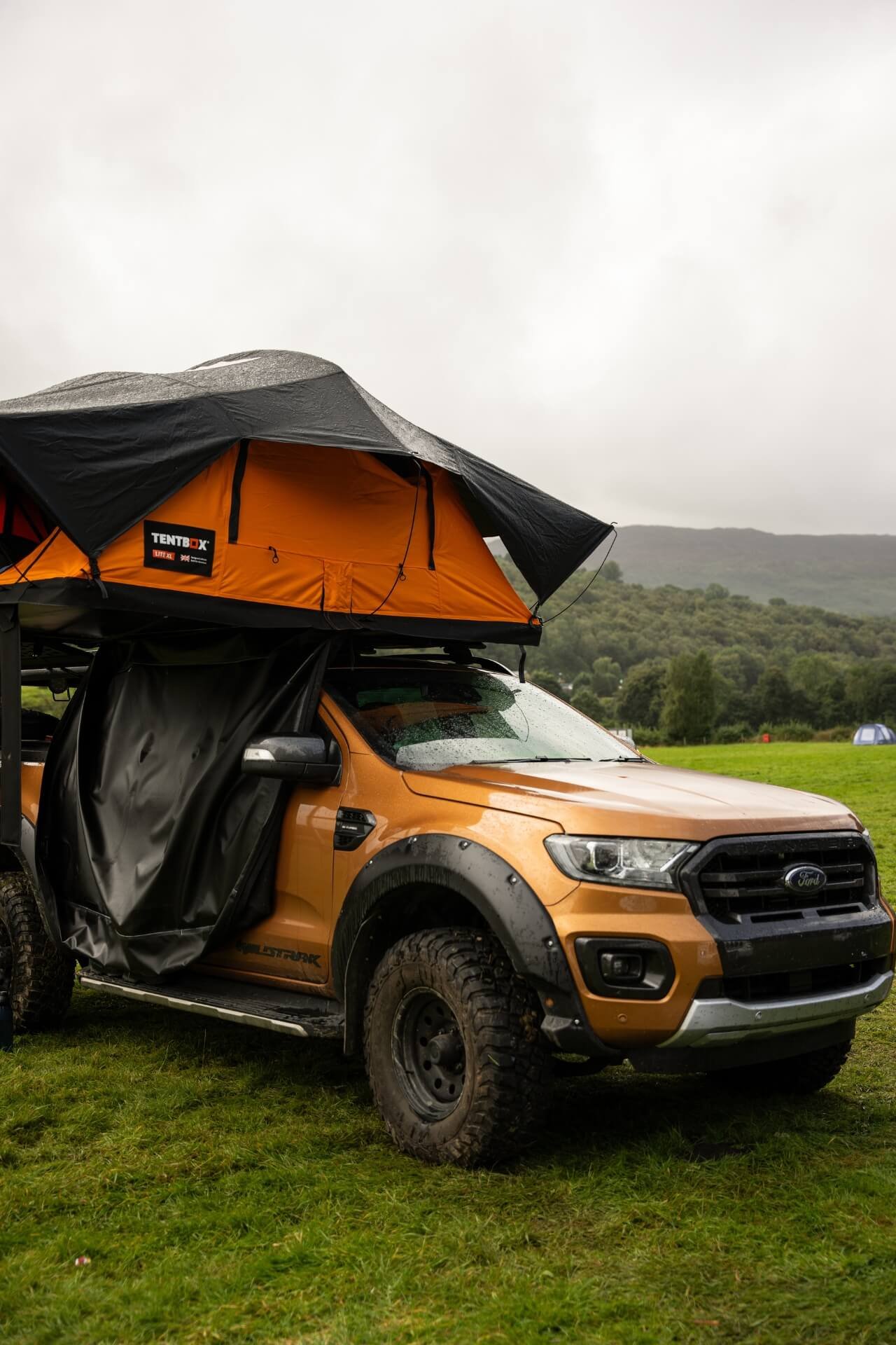 Close-up of a Ford Ranger with Tentbox tent placed on top of it in Wales with forest in the back