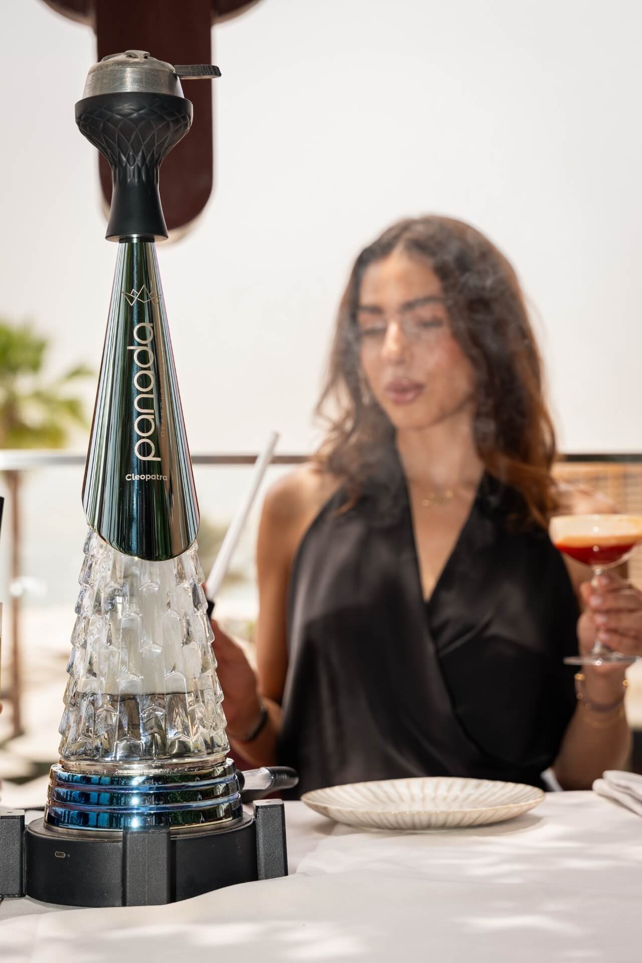 Panada shisha focused on the table with girl smoking shisha in the background