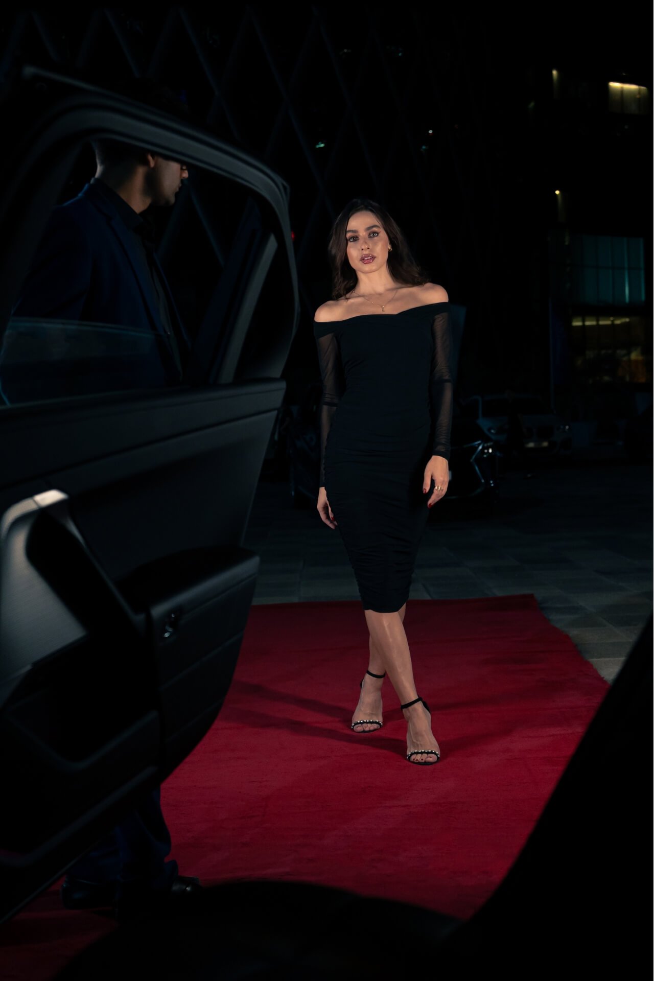 Lady with black dress on the red carpet going inside the car with valet holding the door