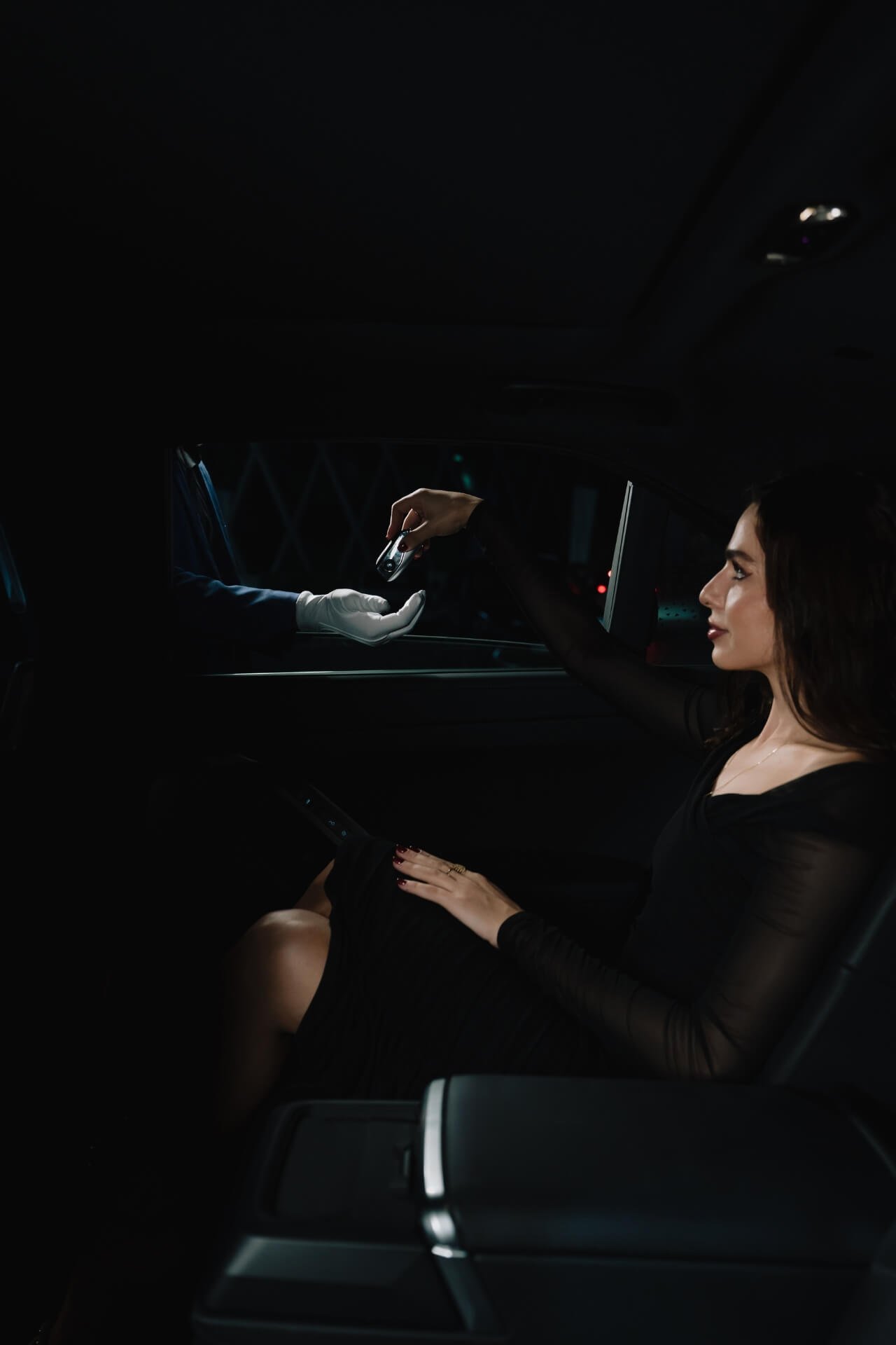 Lady in the back of the car with window open handles the key to valet