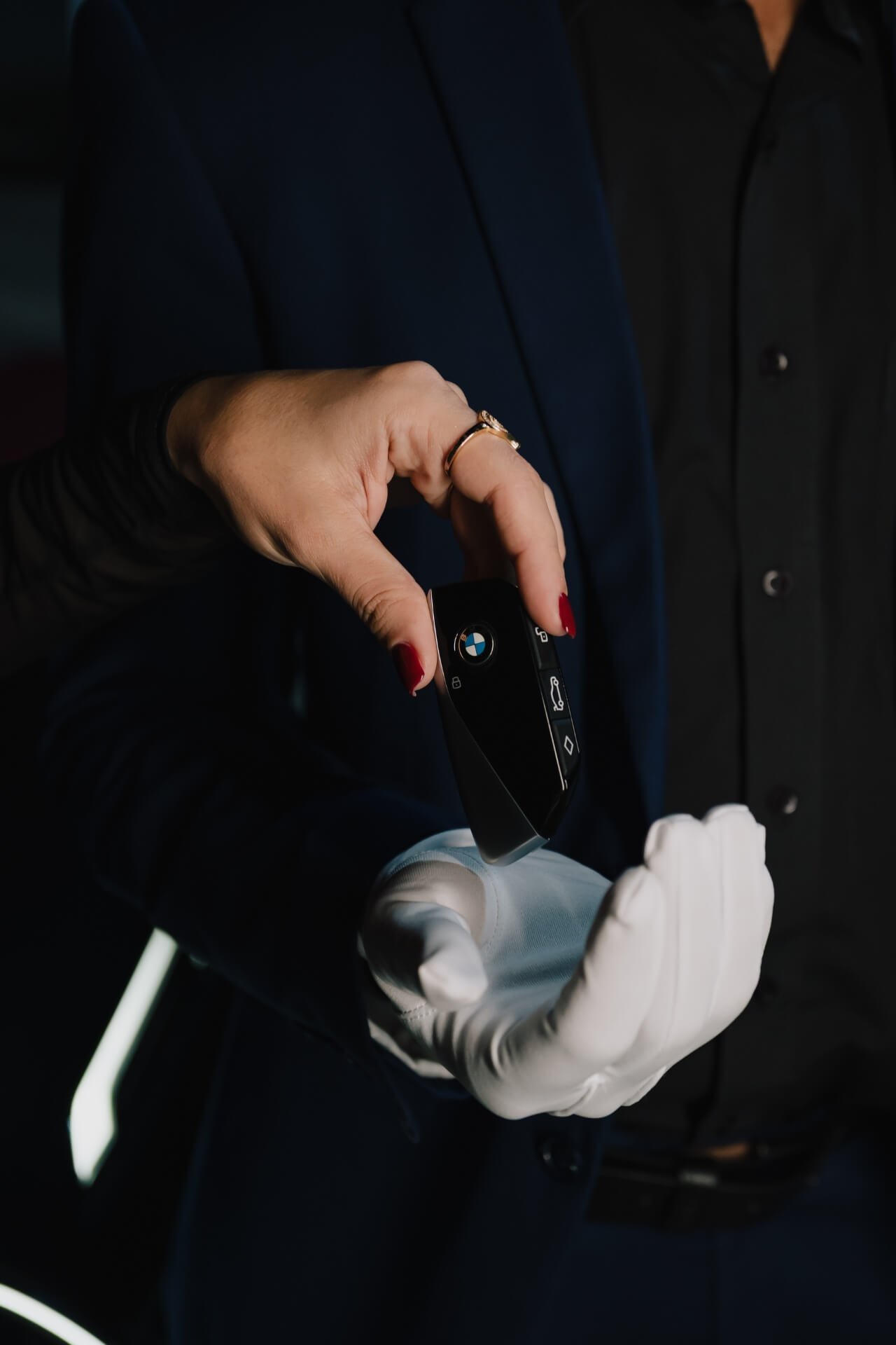 Lady drops a BMW key into the hand of the valet wearing white gloves