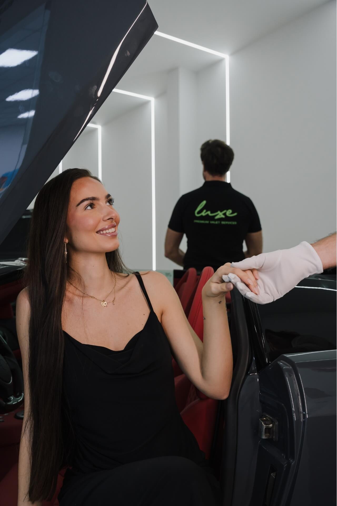 Lady stepping out of a Lamborghini Murcielago, one valet giving a hand as help and other valet posing in the back next to the car